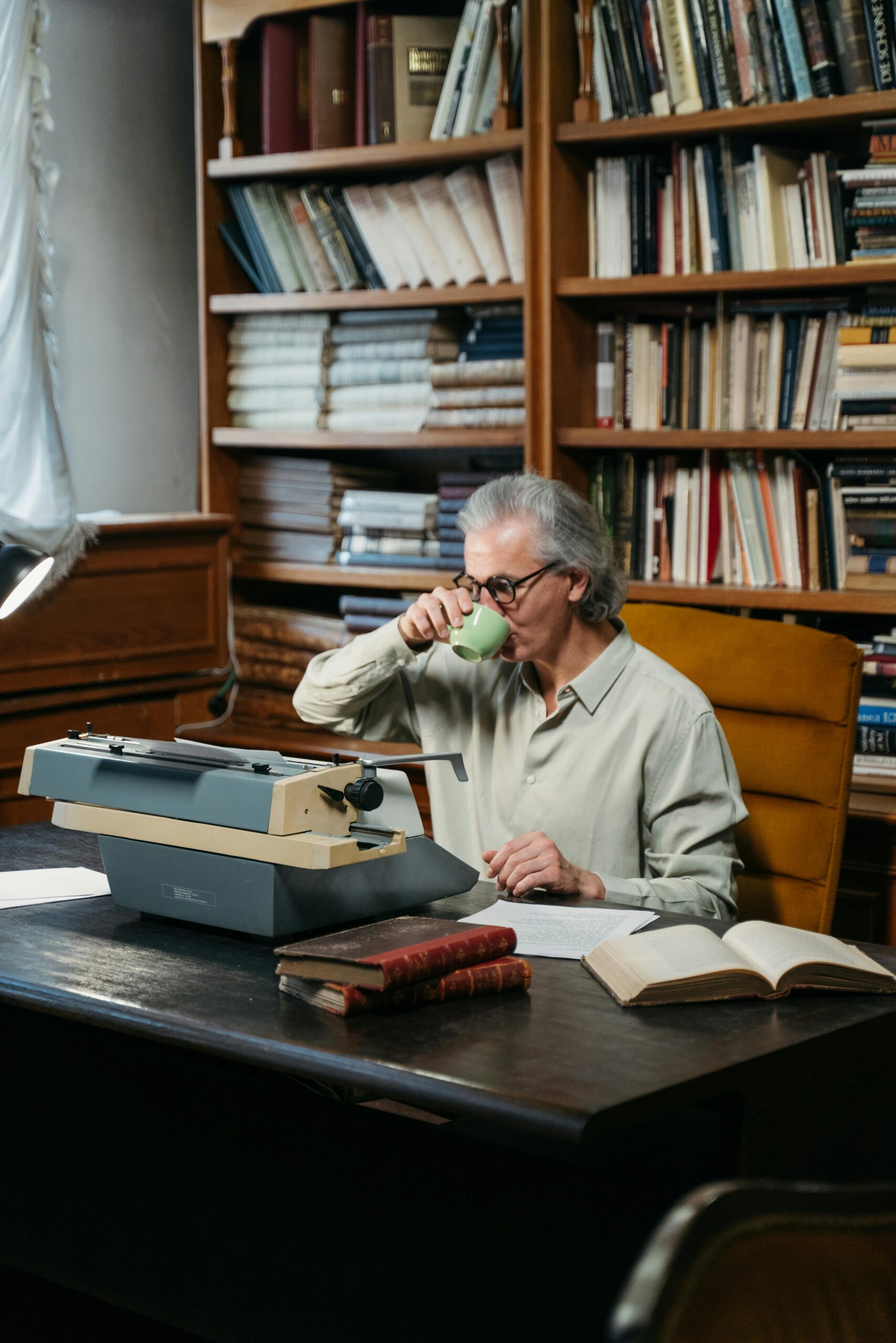 図書館でコーヒーを飲みながら本を読むシニア男性
