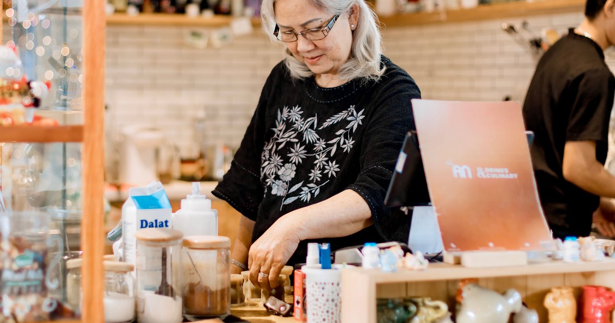 売店のカウンターの中で、手を動かしながら働く60代の女性