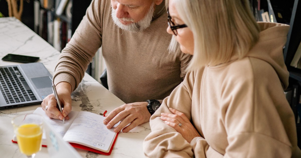 ノートに書き込みながら65歳以降の計画を立てる60代の夫婦